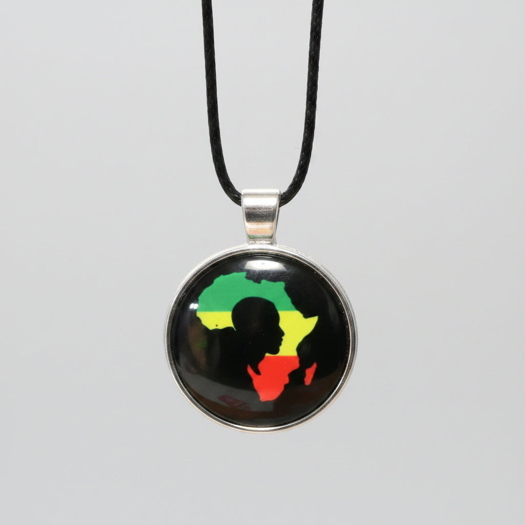 A round pendant necklace on a black cord, featuring a black background with a silhouette of Africa filled with the green, yellow, and red Rastafarian flag colors, set in a silver-toned bezel.