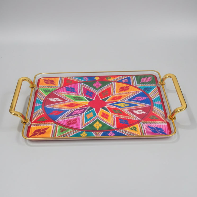 A rectangular decorative tray with gold-toned metal handles and a vibrant, multicolored geometric star pattern on the top, displayed on a black marble surface.