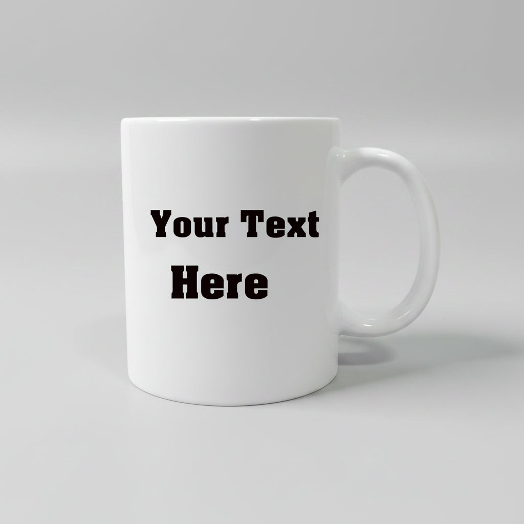 A white ceramic mug with a black printed placeholder text 'Your Text Here' on the front, sitting on a light brown wooden surface against a white background.