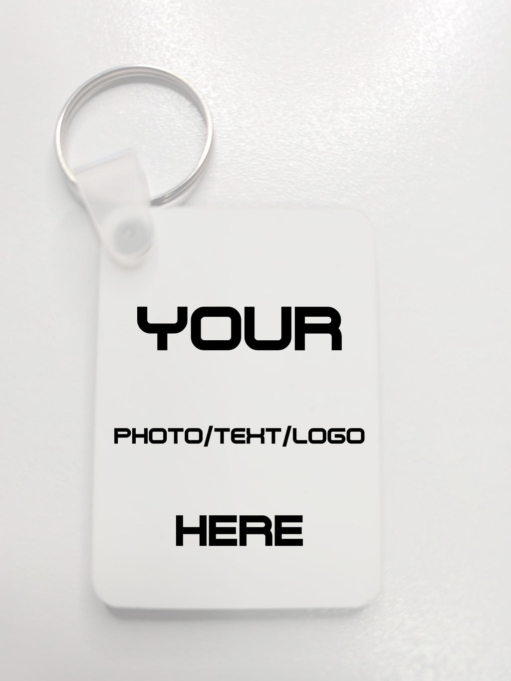 A white customizable rectangular key tag with a silver split ring, featuring placeholder black text that reads 'YOUR PHOTO/TEHT/LOGO HERE' on a light gray background.