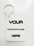 A white customizable rectangular key tag with a silver split ring, featuring placeholder black text that reads 'YOUR PHOTO/TEHT/LOGO HERE' on a light gray background.