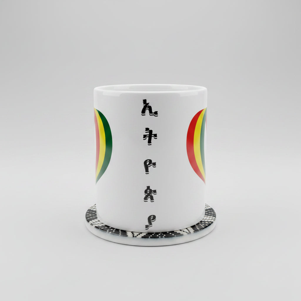 A white ceramic mug featuring the word 'HAPPY' spelled out in black Rastafarian-style letters, flanked by green, yellow, and red semicircles. The mug sits on a matching white coaster with a black and white beaded pattern, set against a neutral beige background.