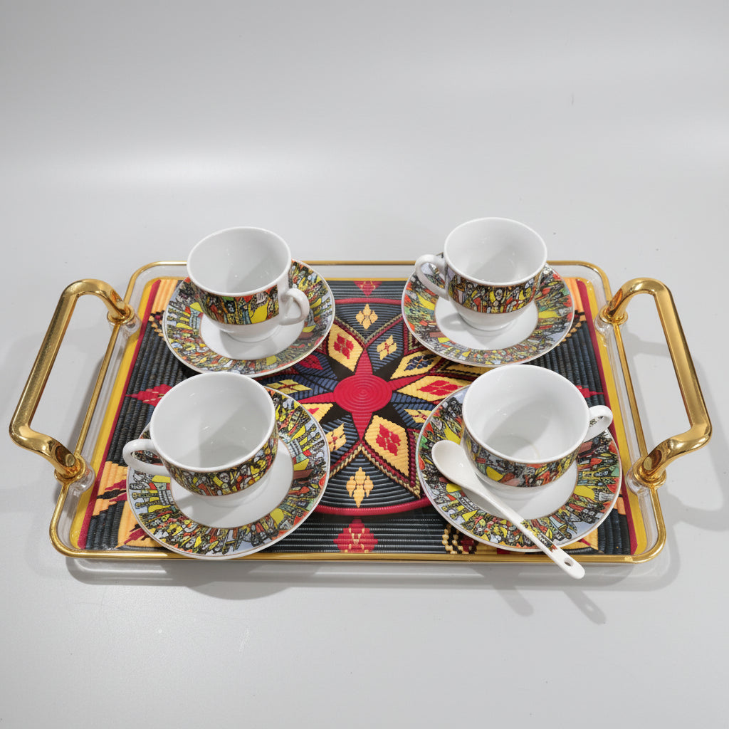 A gold-framed rectangular serving tray with two handles, holding four white ceramic teacups and saucers decorated with colorful geometric patterns, set on a black marble surface.