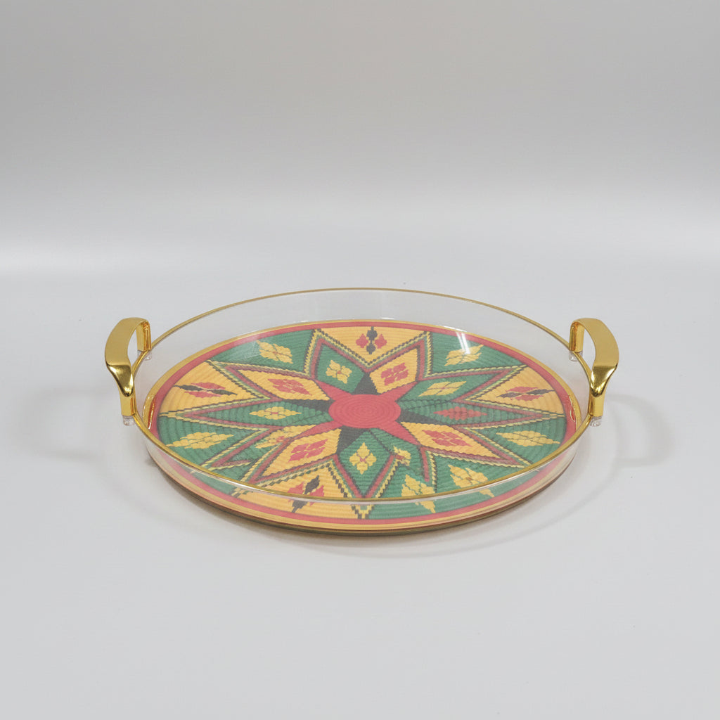 A round decorative tray with gold-toned handles, featuring a colorful geometric starburst pattern in yellow, green, red, and black on a black marble surface.
