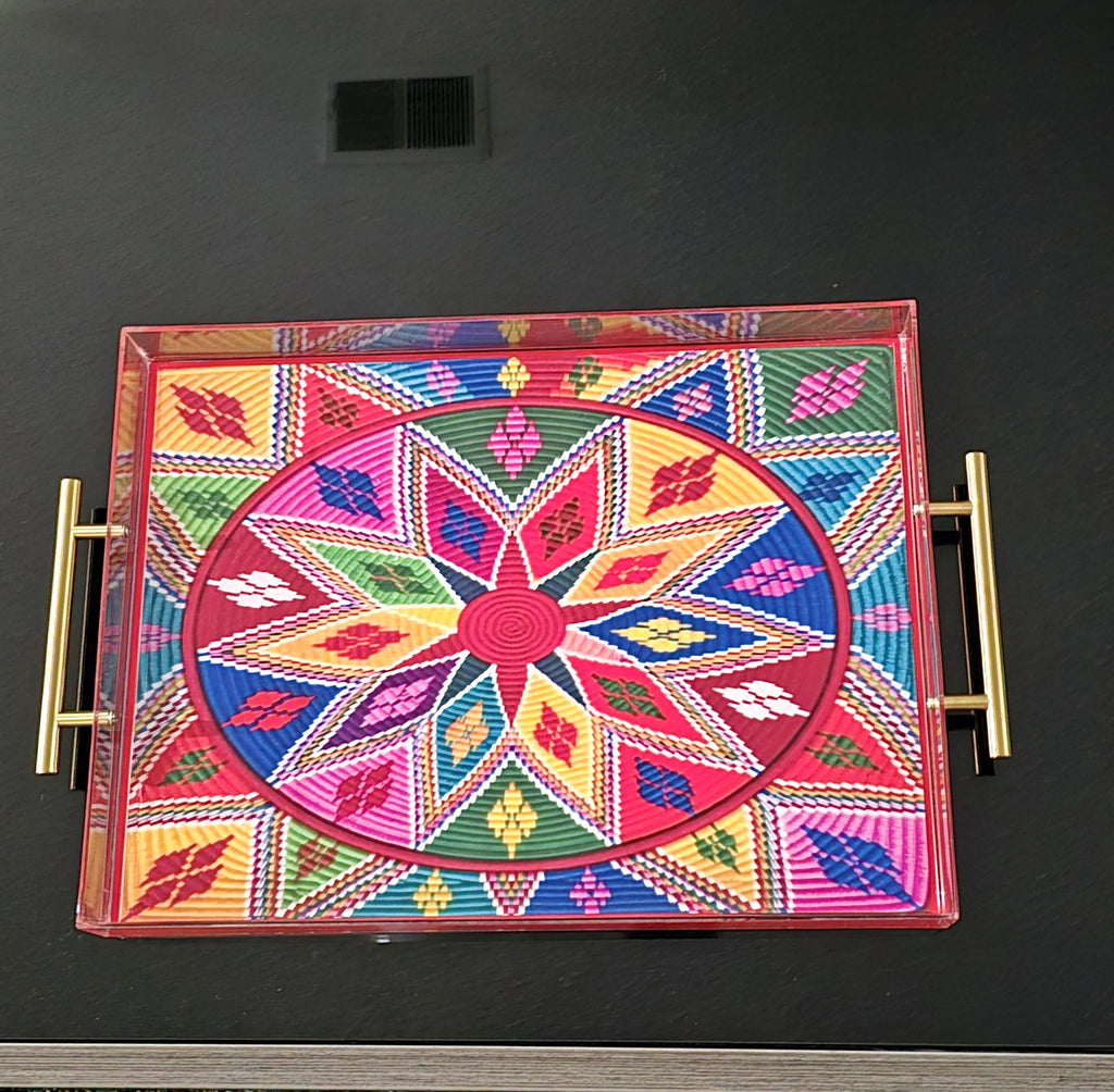 A rectangular acrylic serving tray with gold side handles, featuring a vibrant, multicolored geometric mandala pattern on the lid, set against a dark gray background.