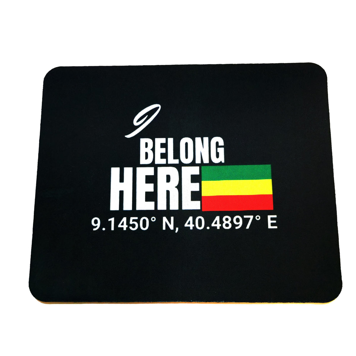 A black rectangular mouse pad with rounded corners featuring a white graphic that reads 'I BELONG HERE' above a small Rastafarian flag and coordinates '9.1450° N, 40.