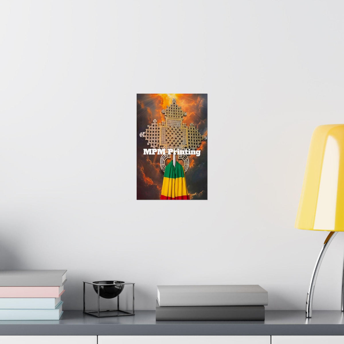 A framed or mounted wall art print featuring a stylized figure in green, yellow, and red with the text 'MFM Printing' appears below, displayed on a white wall above a shelf with books and a yellow lamp.