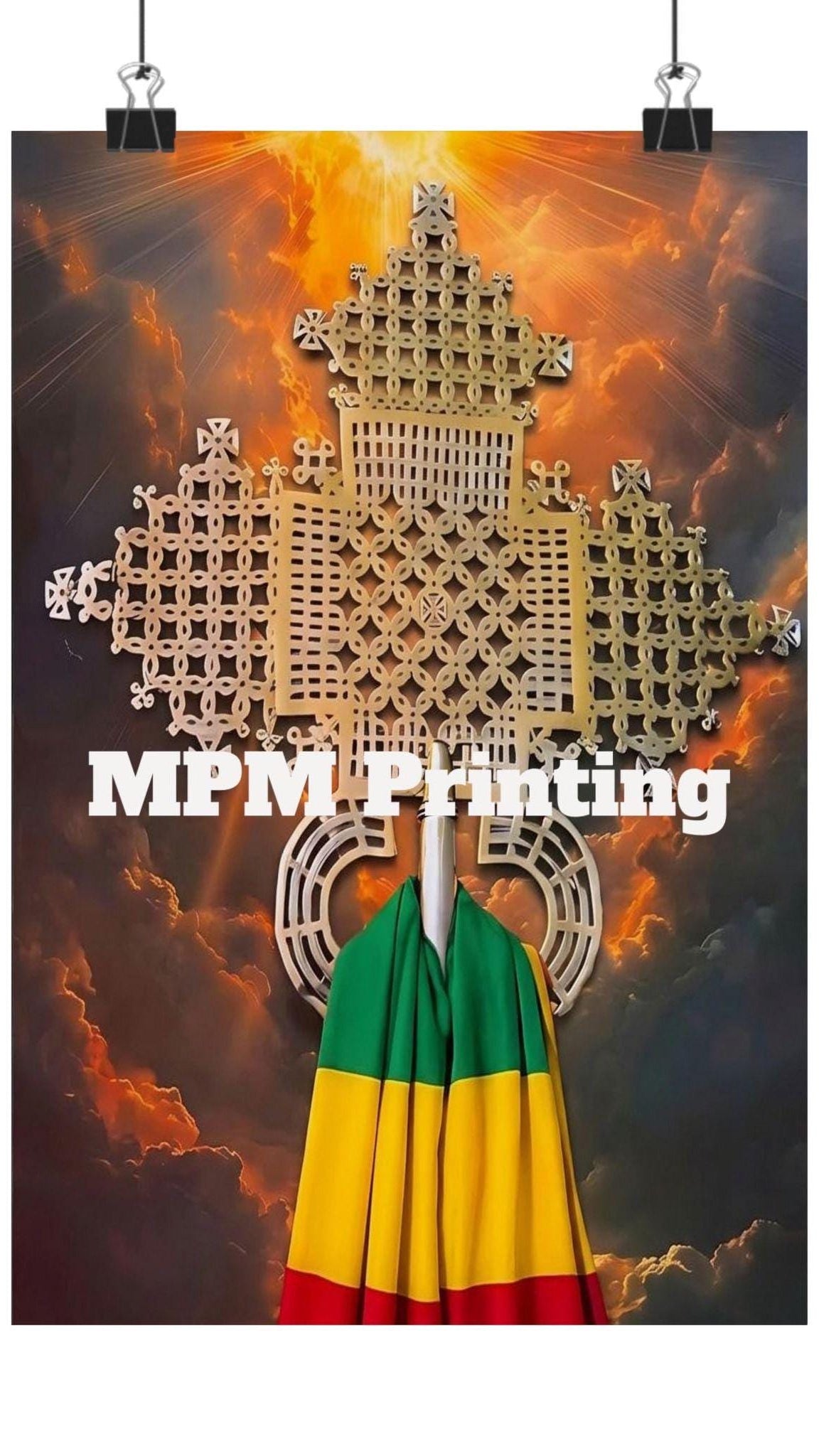 A vertical poster or print clipped at the top with binder clips, featuring a large golden geometric emblem over a dramatic fiery sky background. White text across the center reads 'MPM Printing', and a small Rastafarian flag hangs from a pole at the bottom center.