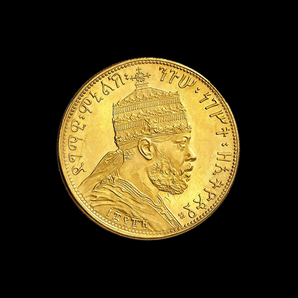 A round gold coin featuring a detailed profile portrait of a Ethiopian emperor Menelik II wearing a crown, surrounded by inscribed script, shown against a solid black background.