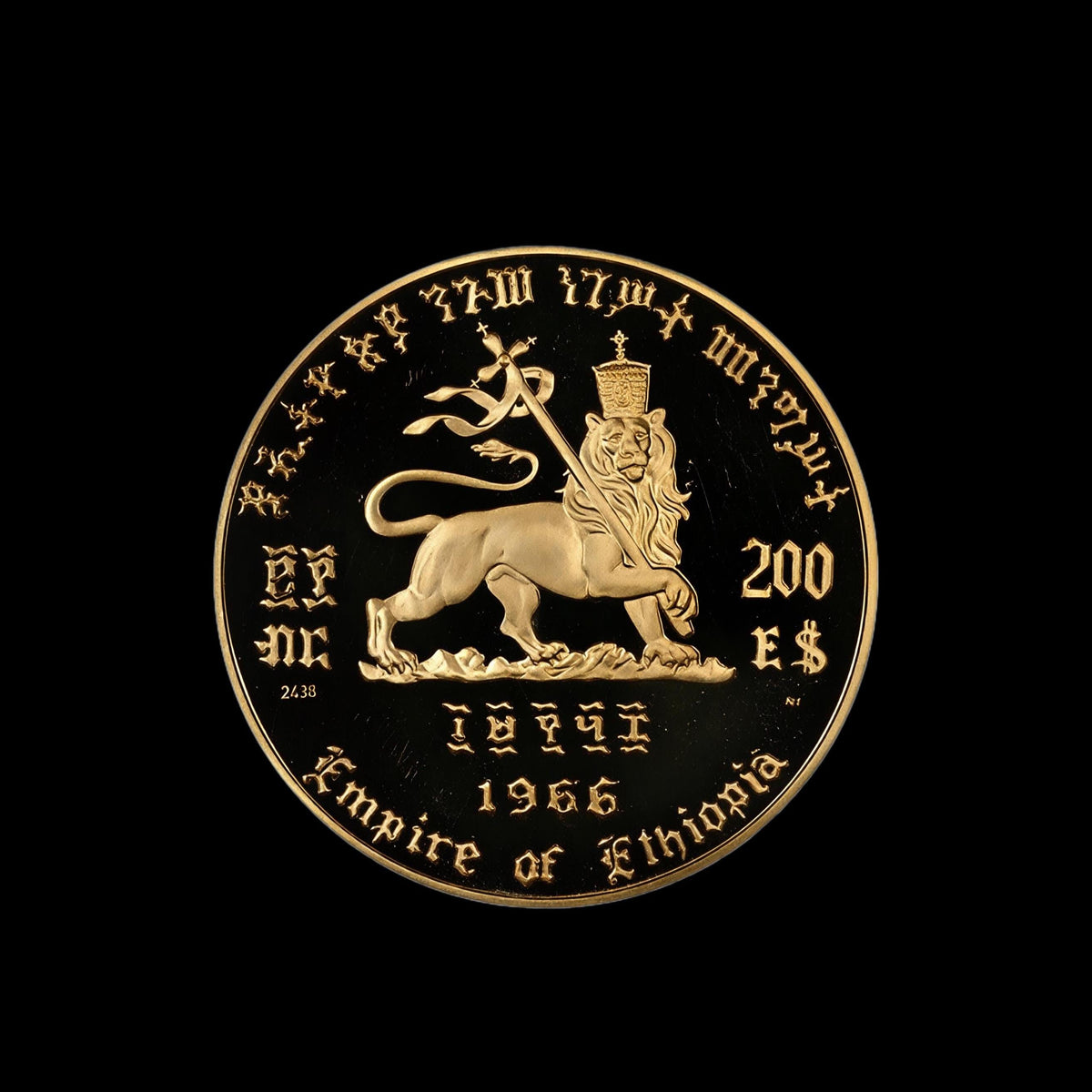 A round gold-colored commemorative coin for the Empire of Ethiopia, featuring a lion rampant and inscriptions, shown against a solid black background.