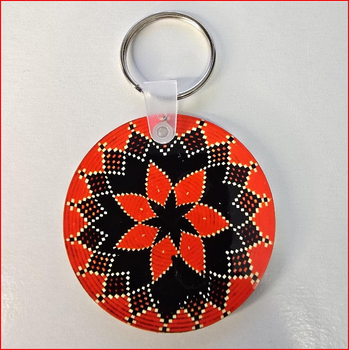 A round acrylic keychain featuring a hand-painted geometric pattern in red, black, and white, attached to a silver metal split ring.