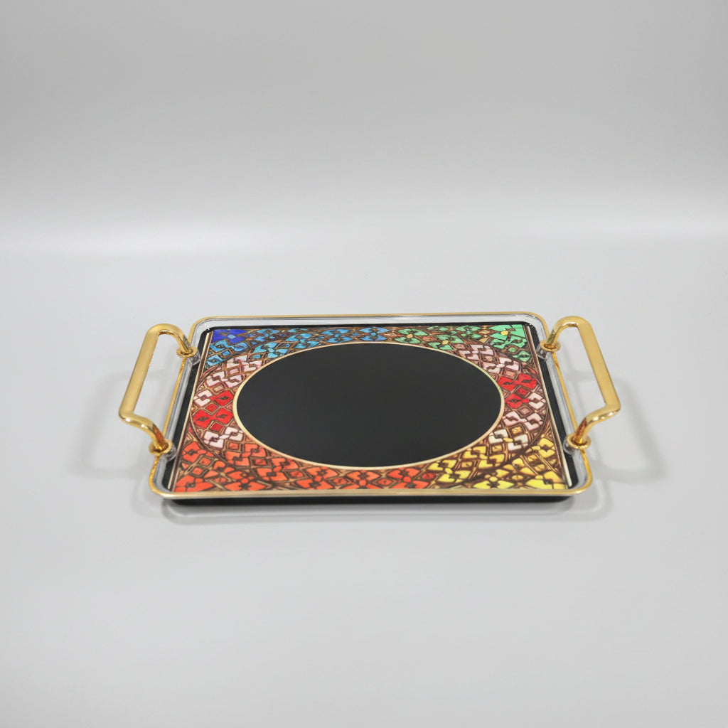 A rectangular gold-framed tray with two side handles and a colorful mosaic pattern around an oval mirror, placed on a black marble surface.