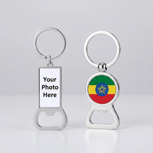Two silver metal keychain bottle opener keychains shown side by side on a light gray reflective surface. One keychain is shown from the front with a blank white rectangular panel, and the other is shown from the back with a blank white circular panel.